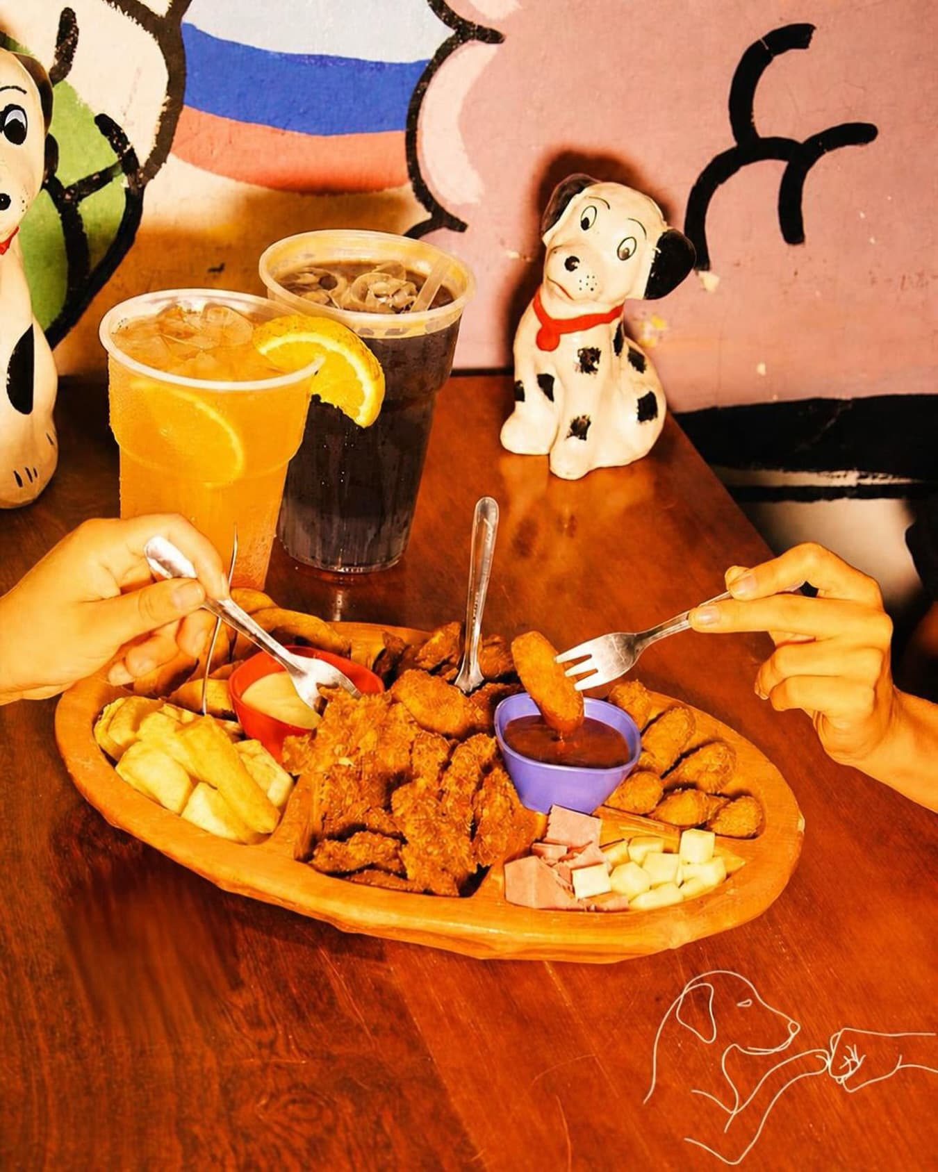 Amigos compartiendo una picada y tragos junto a las figuras de dálmatas del bar